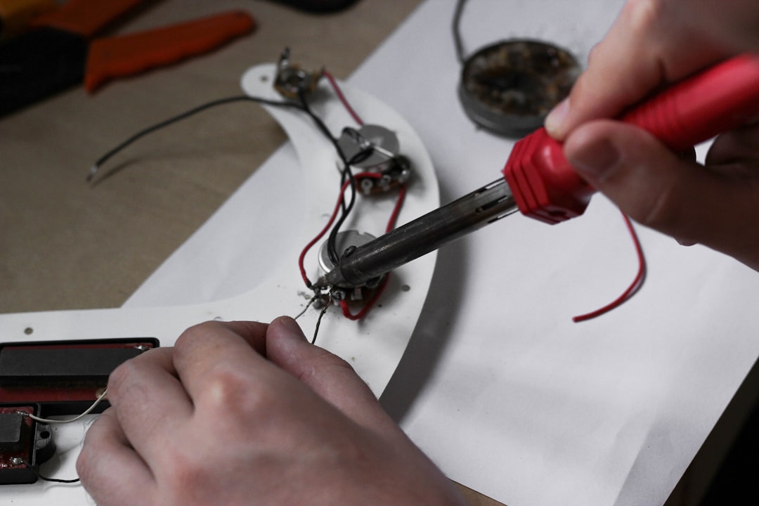 our-story Master with a soldering iron repairs the electronics of a guitar